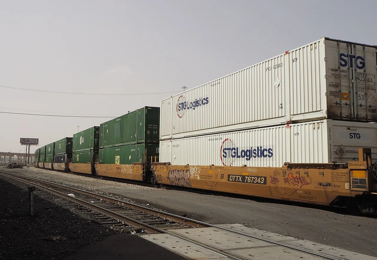 A freight train of double-stacked shipping containers on the tracks in El Paso, with STG Logistics containers on the nearest cars