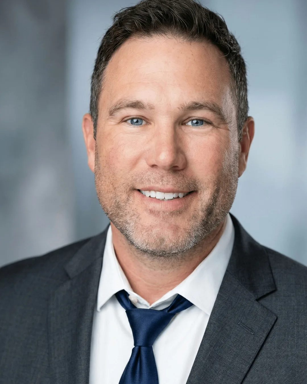Studio portrait of the appraiser in a gray suit jacket, white shirt and navy tie.