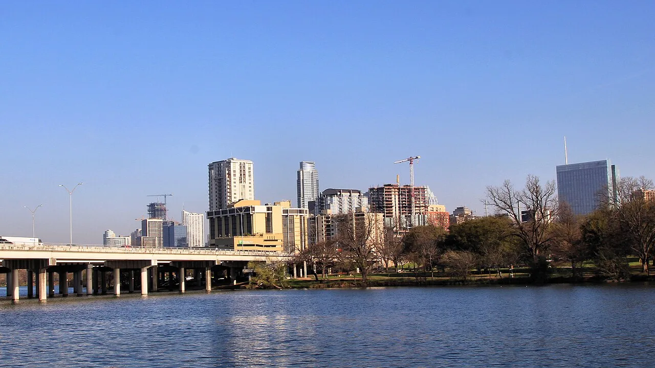 Downtown Austin seen across Lady Bird Lake, with tower cranes over buildings under construction