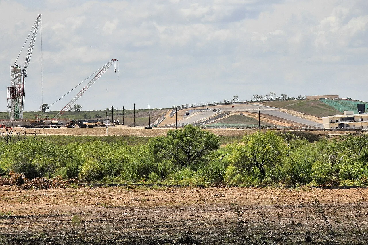 Two lattice boom cranes working beside turn one at Circuit of the Americas near Austin while the track was being paved