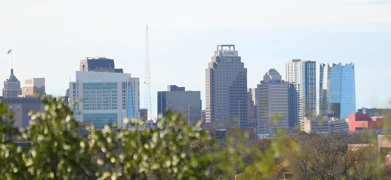 The downtown San Antonio skyline seen over treetops, with the Tower Life Building at the left