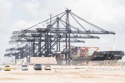 A row of massive ship-to-shore (STS) container cranes servicing a docked cargo vessel at the Port of Houston, illustrating complex intermodal machinery and marine assets subject to heavy equipment appraisal and valuation along the Gulf Coast.